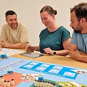 Eine Frau und zwei Männer spielen das FM-Planspiel.