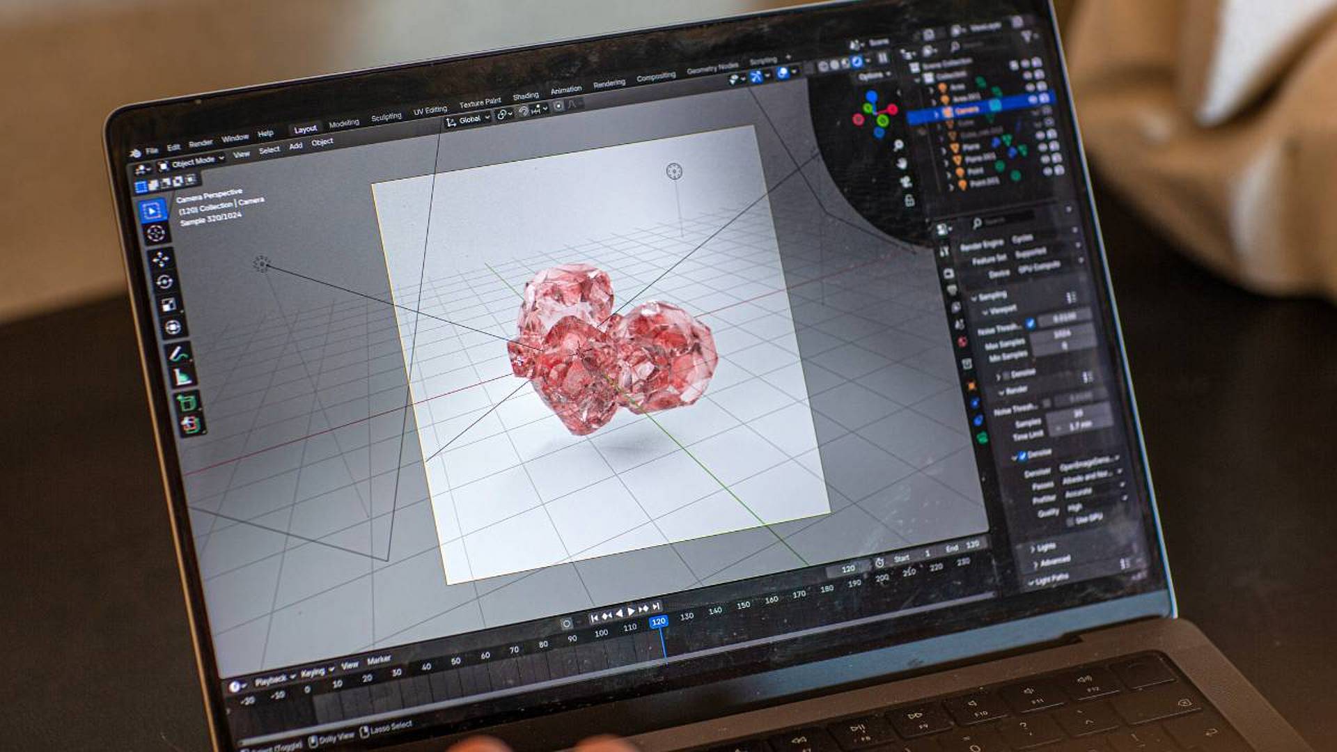 Blender‑Benutzeroberfläche auf einem Laptop mit einem 3D‑Modell aus transparentem, rotem Material im Arbeitsraum.