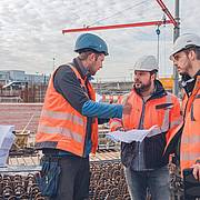 Drei Bauleute kommunizieren auf der Baustelle