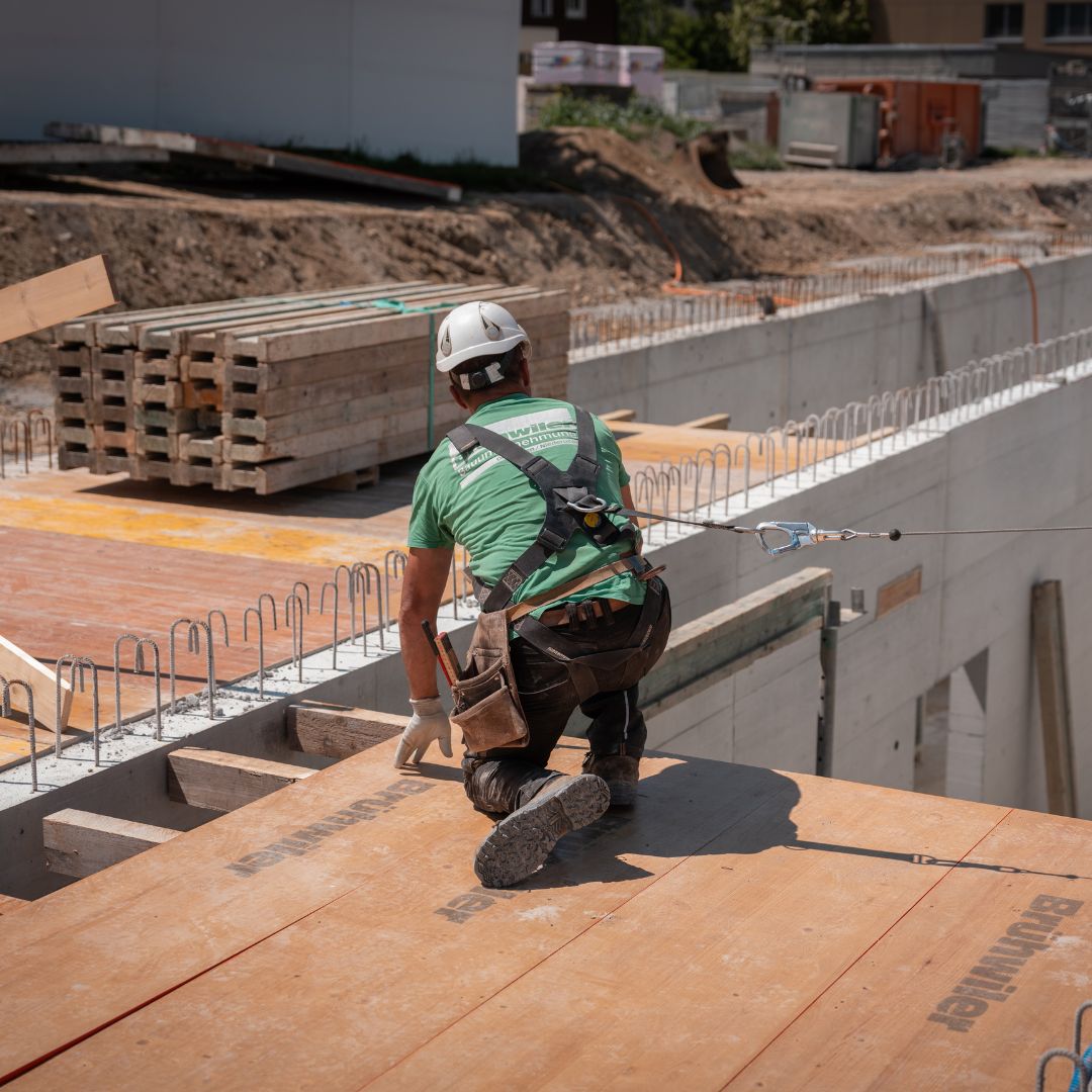 Bauarbeiter mit Sicherheitsausrüstung bei Schalungsarbeiten auf einer modernen Rohbaustelle.